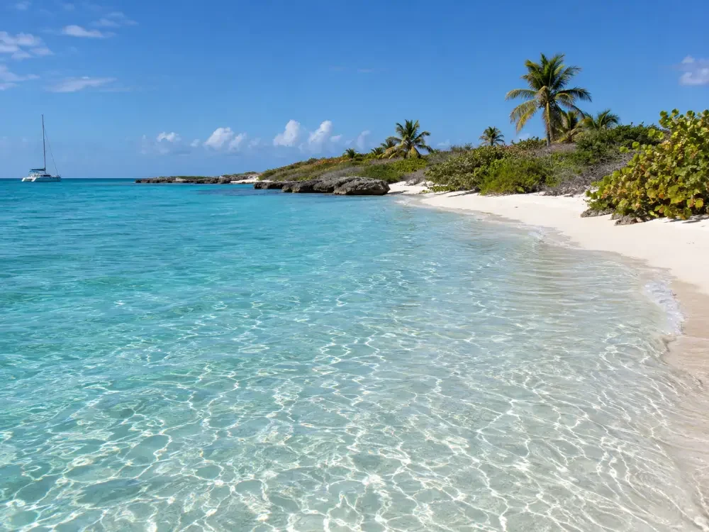 Knee-deep clear water over white sand on the calm side of a small cay